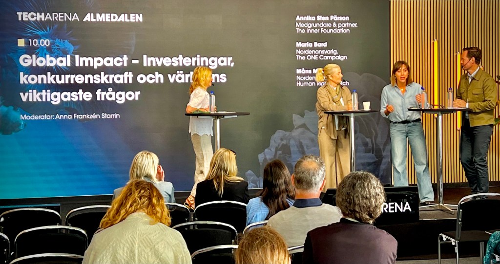 A panel discussion at Almedalen with four speakers, moderated by Anna Frankzén Starrin, focusing on global impact, competitiveness, and important world issues. The backdrop features the event branding and topic text in Swedish.